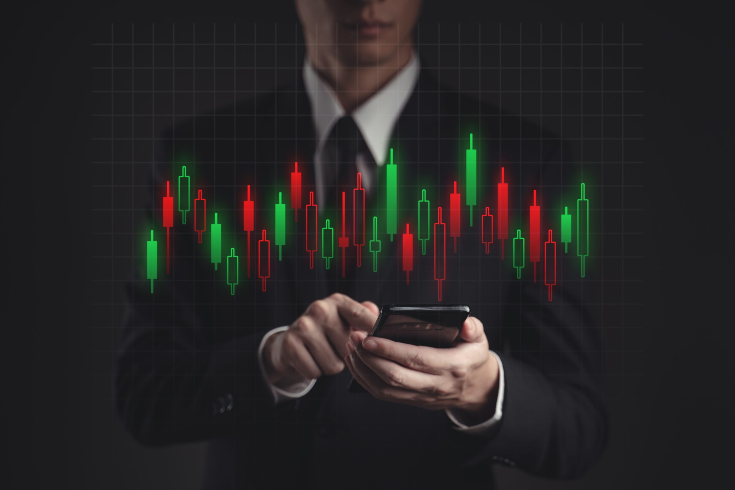 Businessman using smartphone showing candlestick chart hologram Businessman using smartphone showing candlestick chart hologram